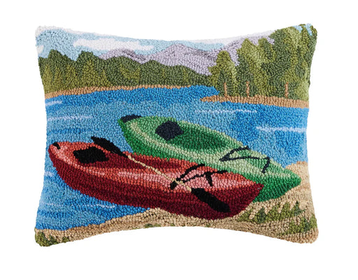 Throw pillow featuring a red and a green kayak sitting on a riverbank against a white background. 