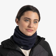 Person wearing a navy blue scarf and black jacket on a white background
