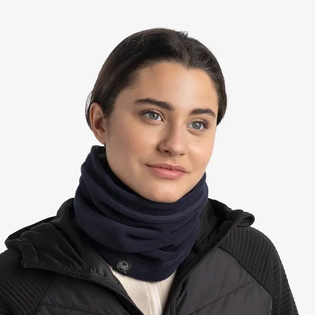 Person wearing a navy blue scarf and black jacket on a white background