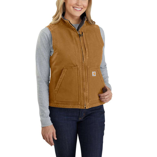 Woman wearing a Carhartt brown colored sherpa-lined vest against a white background. The vest has one zipper pocket on the chest, as well as two pouch pockets towards the bottom. 