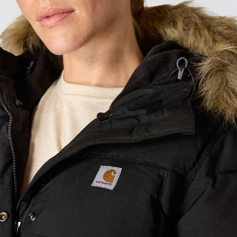 Close up of a woman wearing a black parka with a fur lined hood with a Carhartt logo on the right side of the chest.