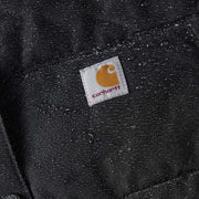 Very close up image of a black parka with water on it. A Carhartt logo is in the center.