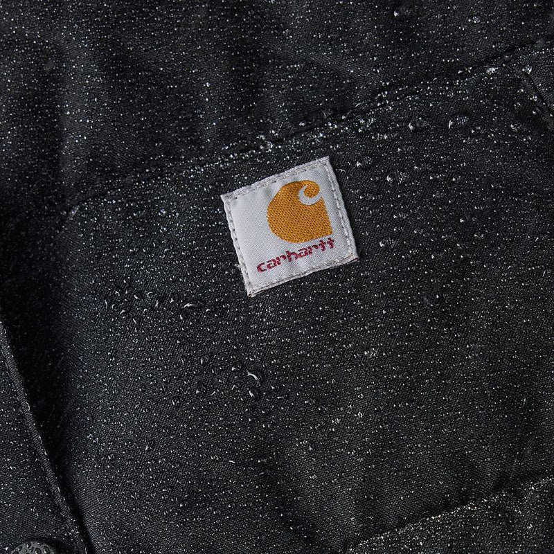 Very close up image of a black parka with water on it. A Carhartt logo is in the center.