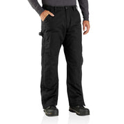 Man wearing loose fitting black work pants with his hand in one of the pockets against a white background.