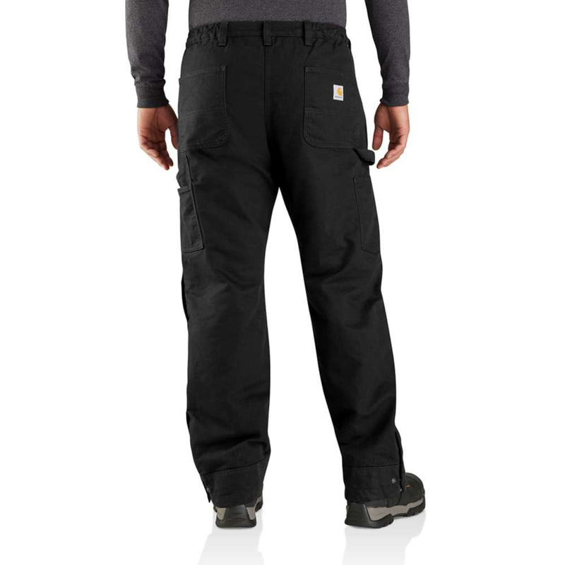 Man wearing a pair of loose fitting black work pants against a white background. There are two pockets and a Carhartt logo on the rear, as well as two pockets on either leg of the pants.