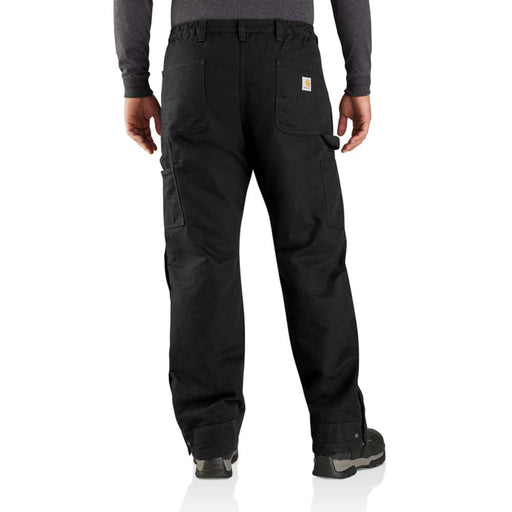 Man wearing a pair of loose fitting black work pants against a white background. There are two pockets and a Carhartt logo on the rear, as well as two pockets on either leg of the pants.
