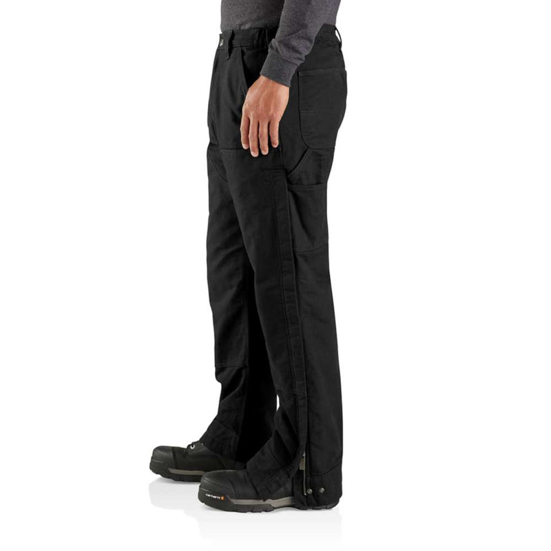 Side view of a man wearing loose fitting black work pants that open up on the side against a white background. 