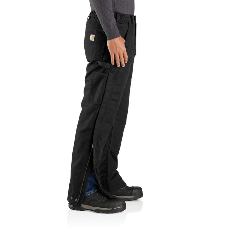 Side view of a man wearing loose fitting black work pants that open up on the sides against a white background. 
