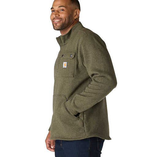 Side view of a man wearing an olive colored fleece jacket with hand in pouch pocket on a white background