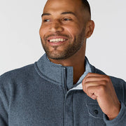 Close-up of a happy man wearing a faded navy colored fleece jacket against a white background