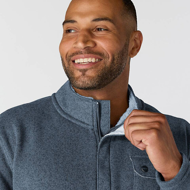 Close-up of a happy man wearing a faded navy colored fleece jacket against a white background