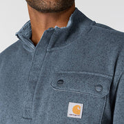 View of a chest pocket on a faded navy fleece jacket a man is wearing on a white background