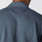 Back view of a man wearing a faded navy colored fleece jacket on a white background