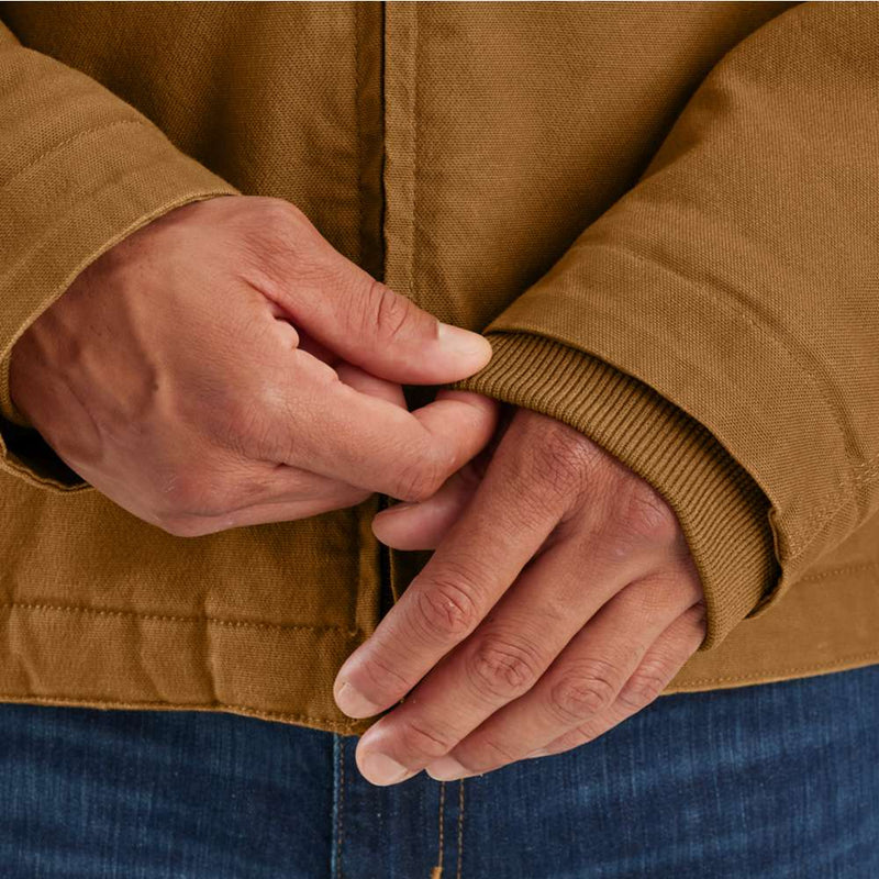 Man pulling down the sleeves of a brown duck lined insulated jacket. 