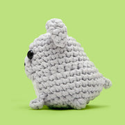 Gray crocheted toy on a green background