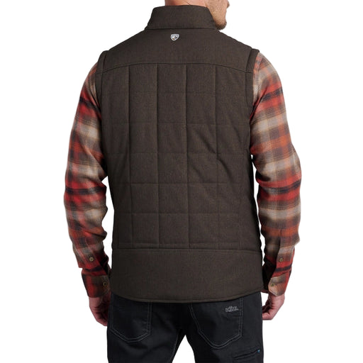 Person wearing a brown quilted vest over a plaid shirt on a white background
