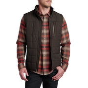 Man wearing a brown vest over a plaid shirt on a white background