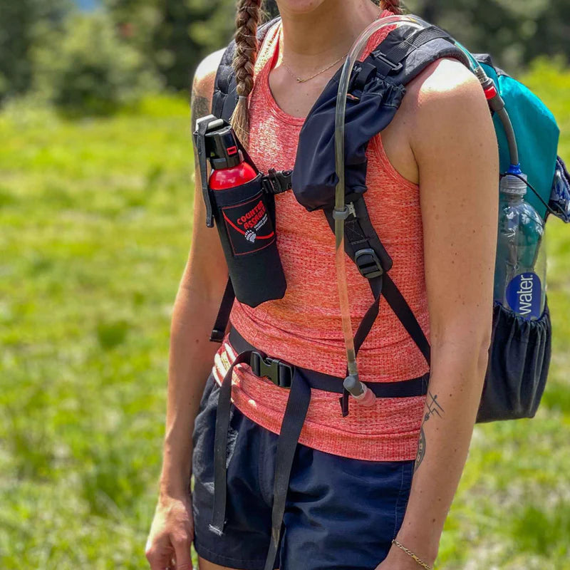 A person outside wearing a backpack with the bear spray holster attached