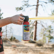 A person outside spraying a can of bear spray