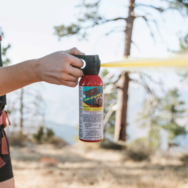 A person outside spraying a can of bear spray