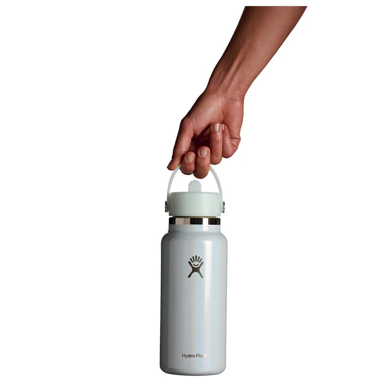 A hand holding the handle of a Hydro Flask insulated water bottle against a solid white background.