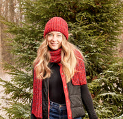 Woman wearing a red knit beanie hanging out in the woods. 