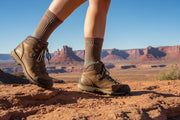 Person wearing brown hiking shoes and brown crew socks while hiking in a canyon.
