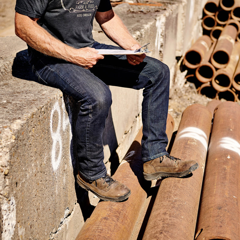 Person sitting on pipes holding a clipboard in an industrial setting