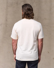 Man wearing a plain white t-shirt against a beige wall