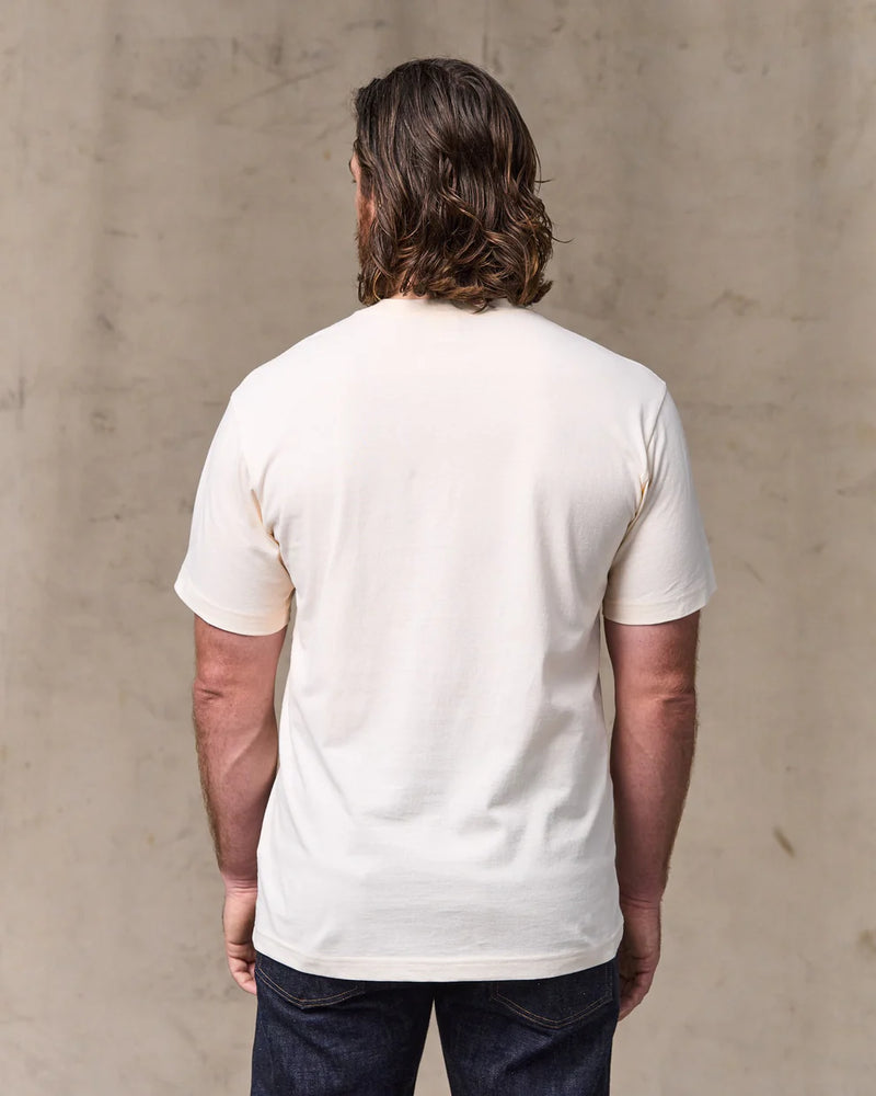 Man wearing a plain white t-shirt against a beige wall