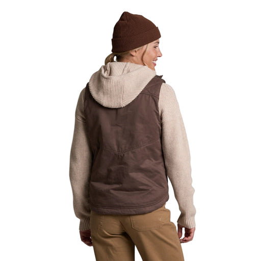 Person wearing a brown vest and beanie on a white background