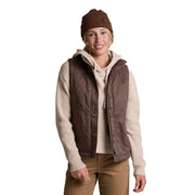 Person wearing a brown vest, beige sweater, and brown beanie on a white background