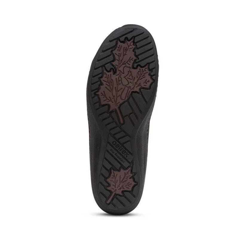 Bottom view of the tread of a shoe that features a dark purple colored leaf pattern on a black sole against a white background. 