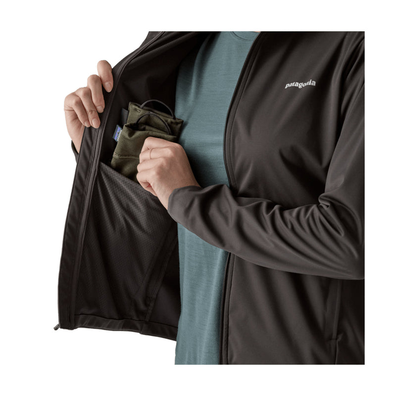 A close-up of a person wearing a black Patagonia zip-front jacket over a muted blue-green shirt, opening the jacket to show a side pocket containing an olive green pouch.