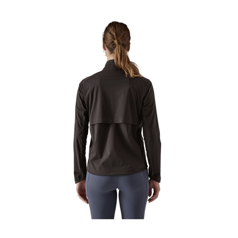 A woman viewed from the back wearing a dark brown long-sleeve athletic jacket and slate blue leggings against a plain white background.