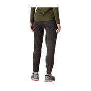 Rear view of a person wearing dark charcoal gray athletic pants, an olive green long-sleeve top, and gray trail running shoes against a plain white background.