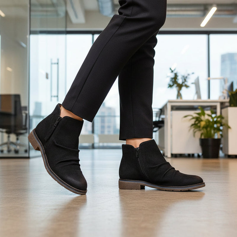 Girl walking through an office wearing a pair of black ankle boots.