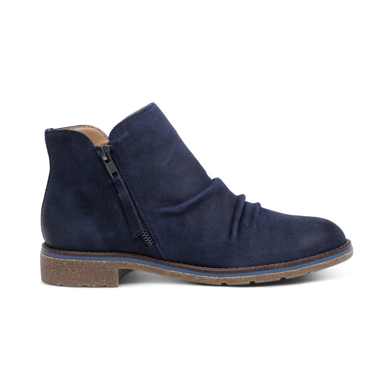 Side view of a blue colored ankle boot against a white background. 