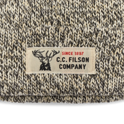 Close up of a white beanie with black accents featuring a Filson logo against a white background. 