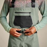 Man adjusting the buckle of his sage colored waders.