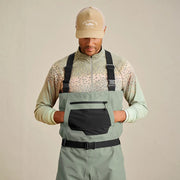 Man putting his hands in the pouch pocket of his sage colored waders. 