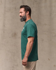 Man wearing a green t-shirt against a beige wall