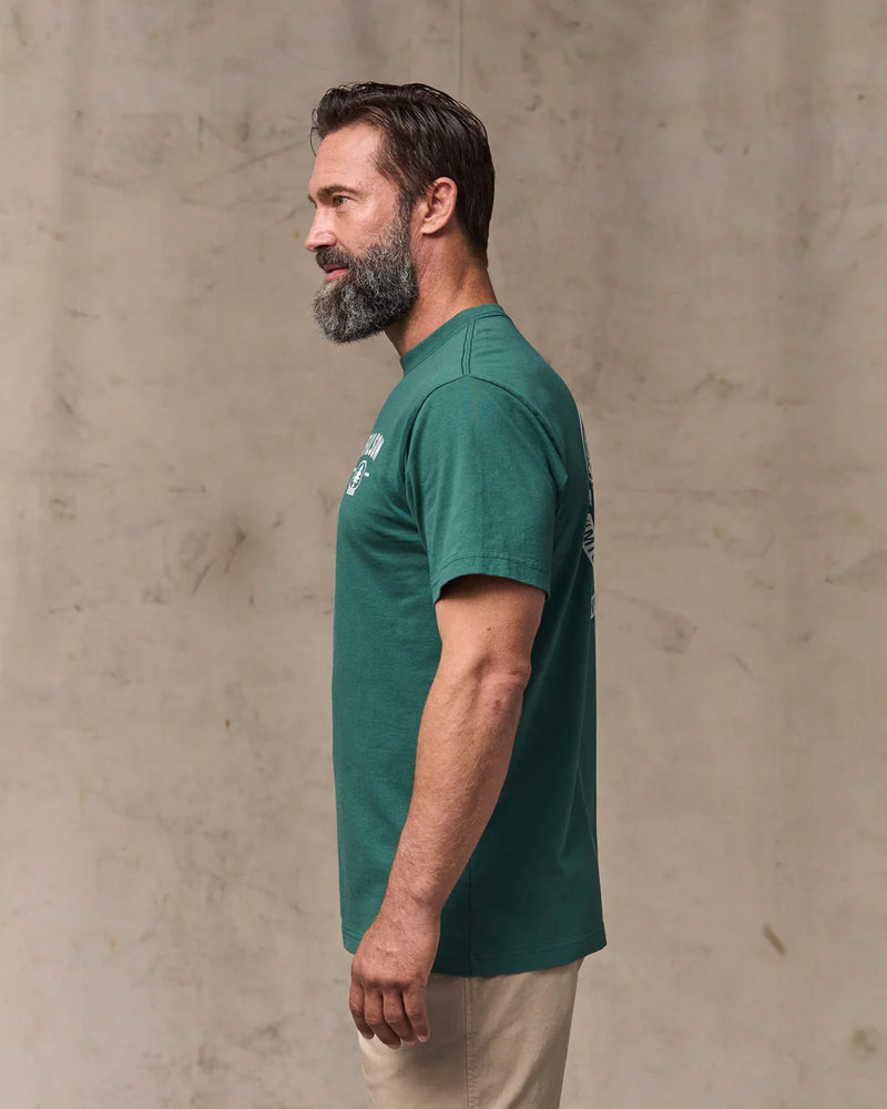 Man wearing a green t-shirt against a beige wall