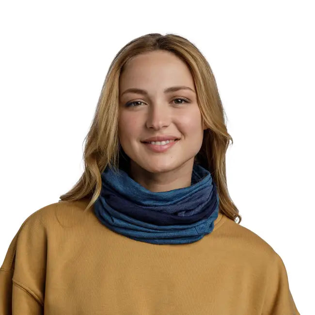 Smiling woman wearing a blue neck gaiter against a white background. 