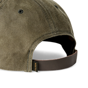 Close up back view of an olive green colored baseball cap featuring a Filson logo against a white background. 