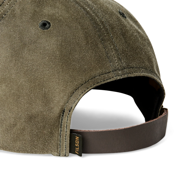 Close up back view of an olive green colored baseball cap featuring a Filson logo against a white background. 