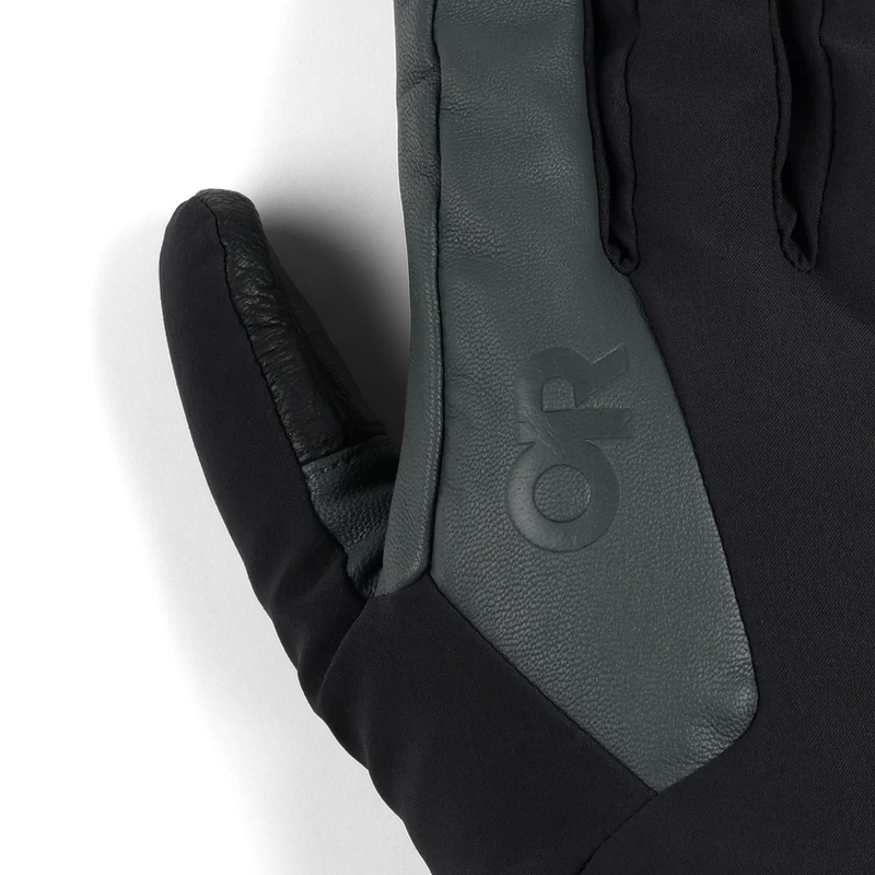 Close up of the thumb of a black and gray work glove featuring an Outdoor Research logo against a white background. 