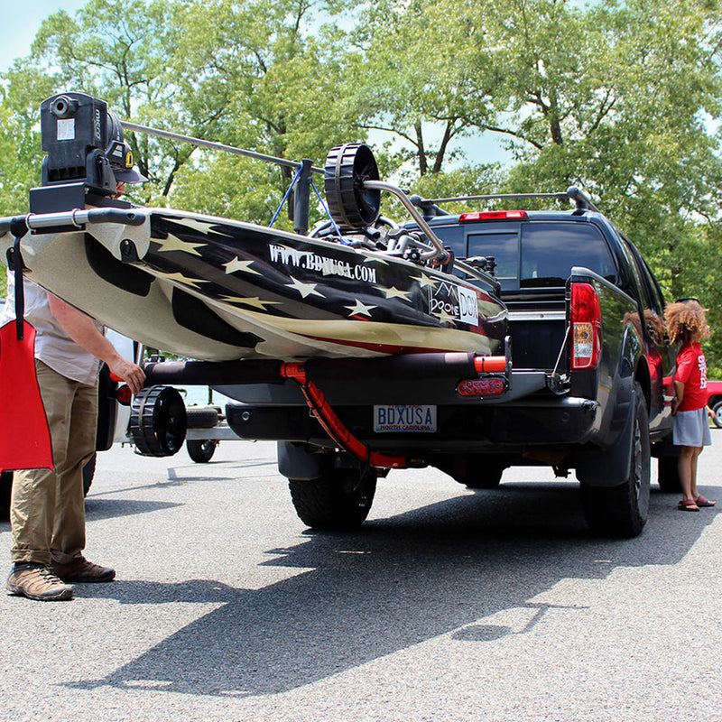 Red extender holding up an Americana patterned boat with people and trees in the background.