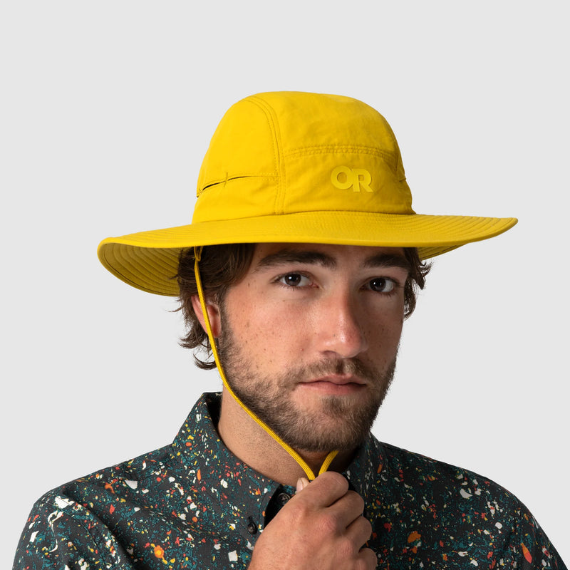 Person wearing a yellow outdoor research hat on a light gray background