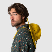 Man wearing a colorful jacket with a yellow hood against a plain background